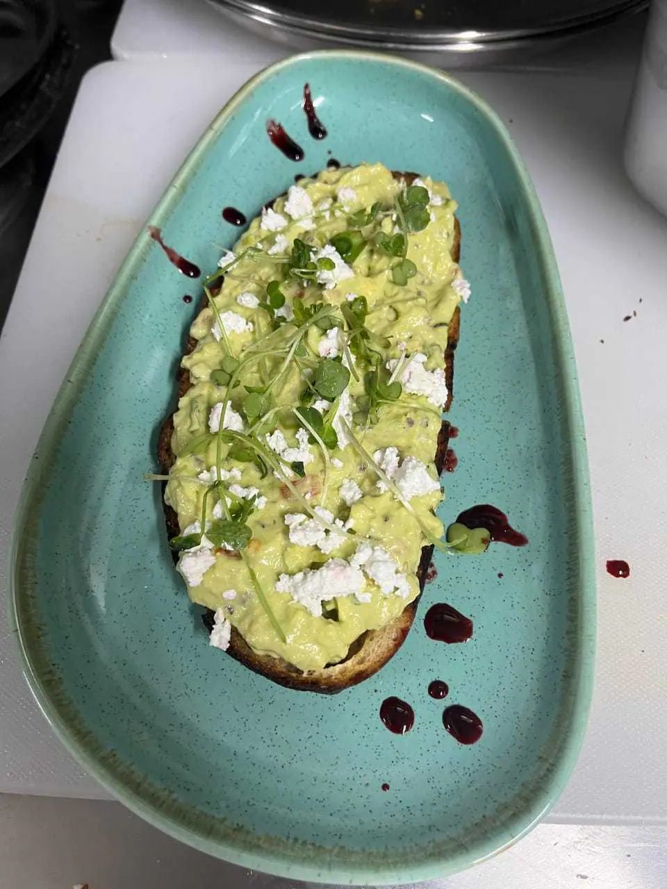 Smashed avocado and feta on toast, plated with a balsamic swirl