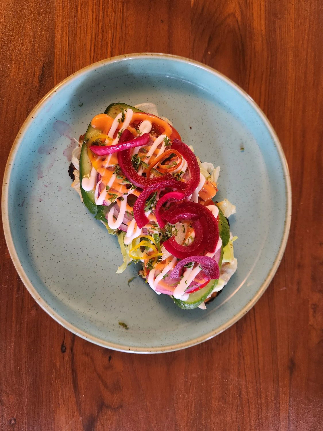 Avocado toast with pickled onion, tomato and herbs on a grey plate
