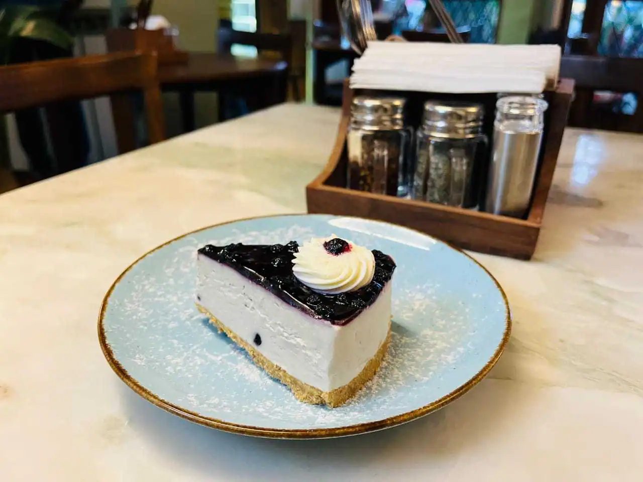 A slice of blueberry cheesecake on a pale blue plate