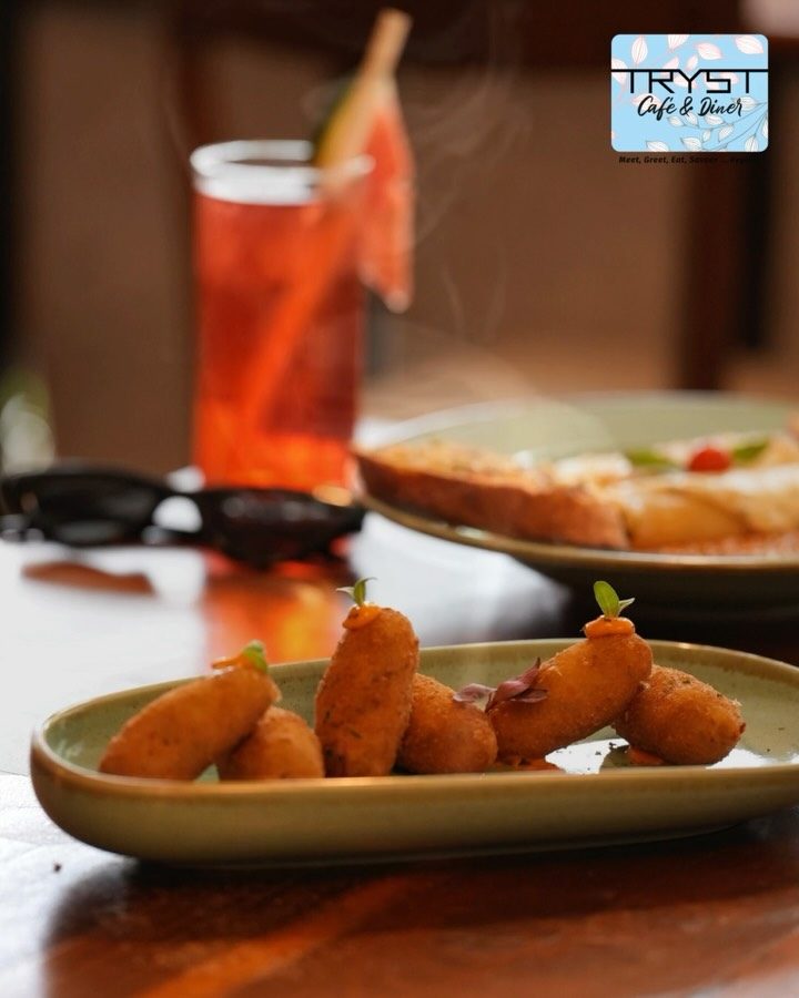Golden cheese corn nuggets on an olive plate beside an iced tea