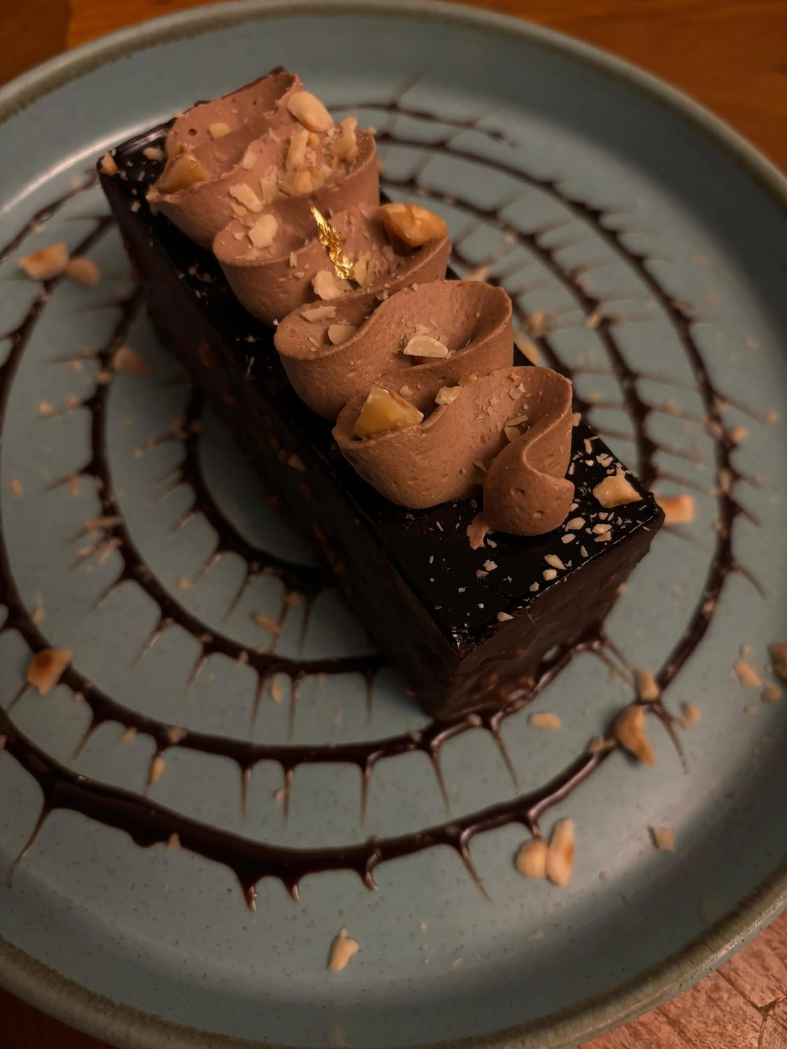 A slice of chocolate truffle cake with hazelnut, on a chocolate swirl