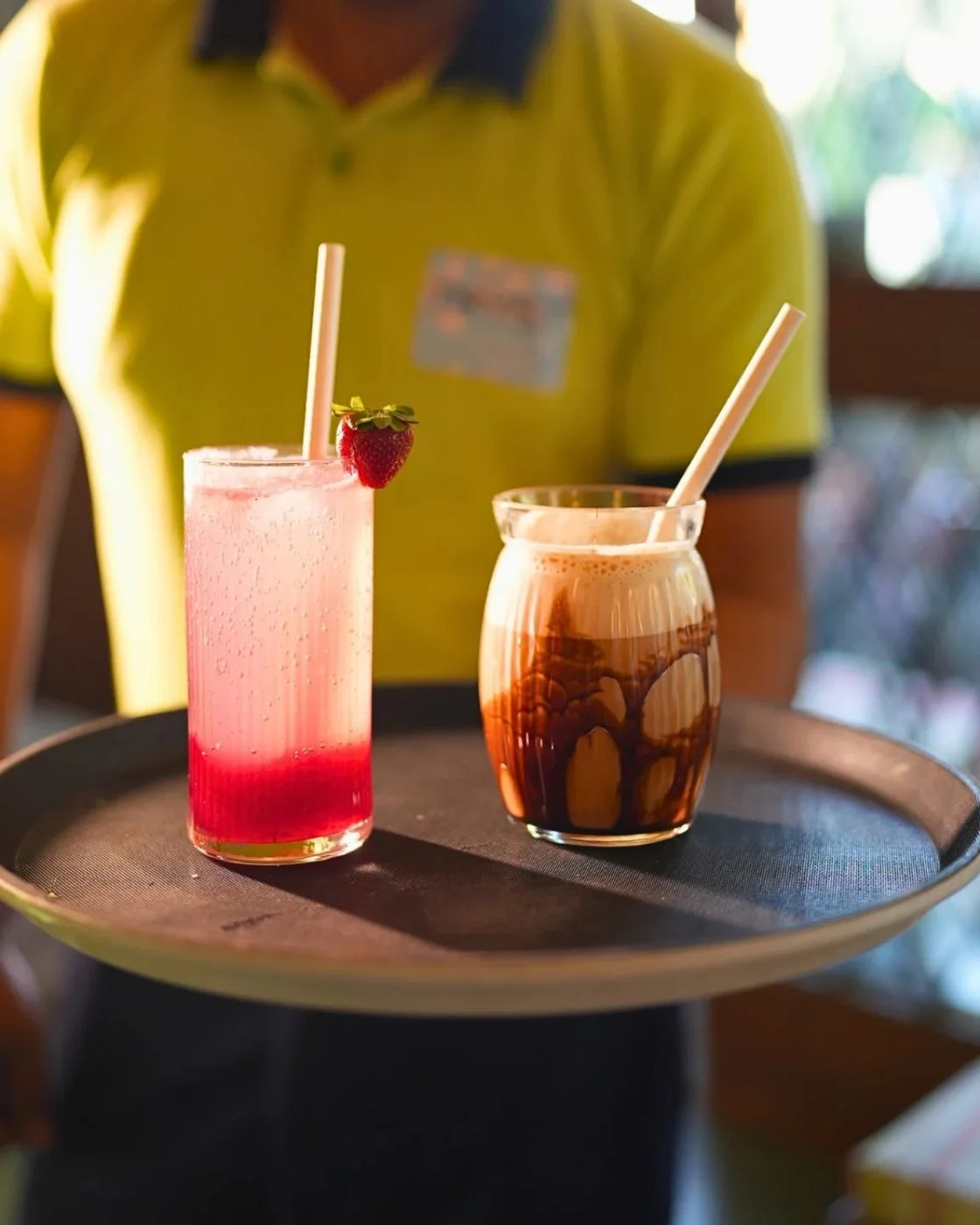 A strawberry cooler and an iced coffee carried out on a round tray