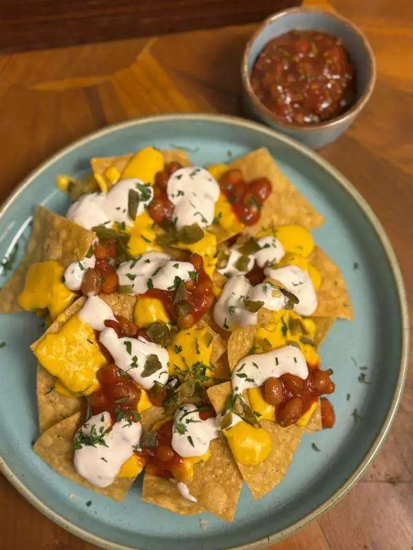 Nachos with mango salsa, sour cream and a bowl of tomato salsa
