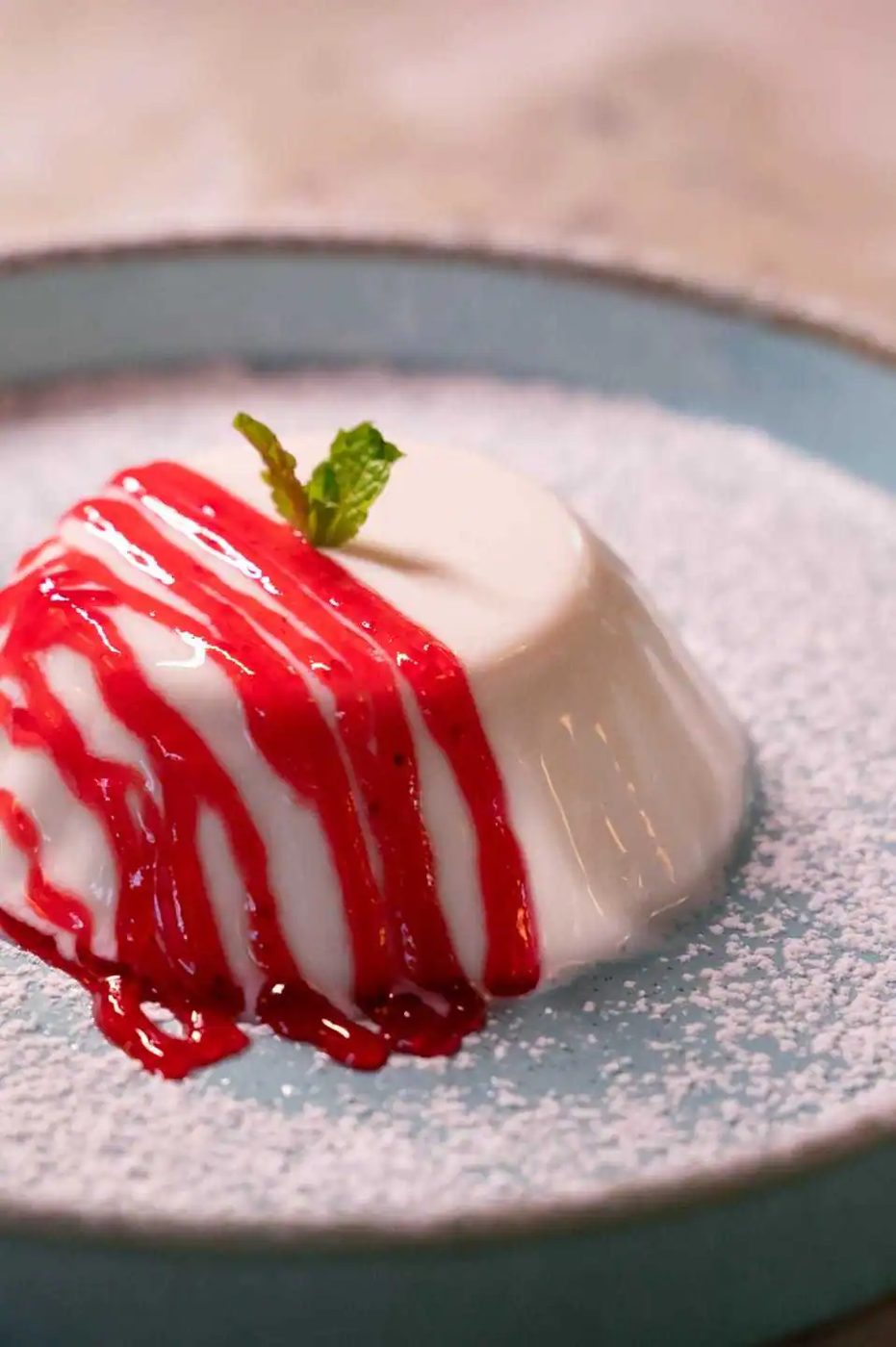 Panna cotta under a raspberry drizzle, dusted with sugar