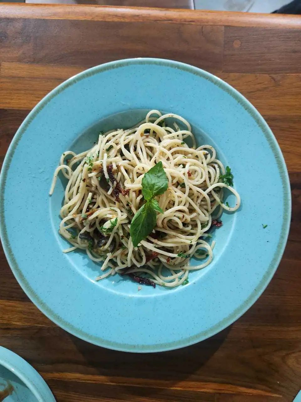 Spaghetti tossed with herbs and basil on a blue plate