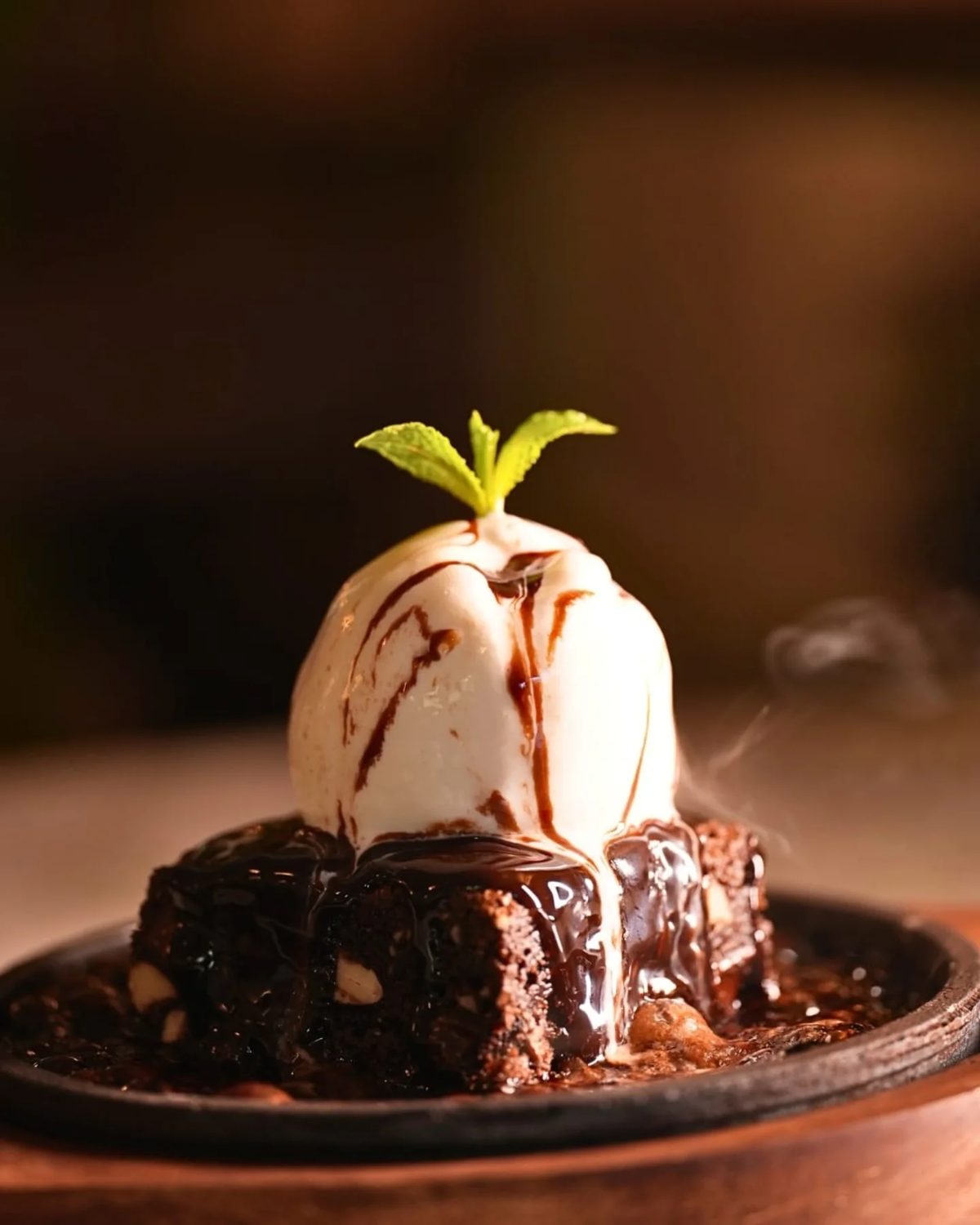 Warm brownie topped with vanilla ice cream on a cast iron plate