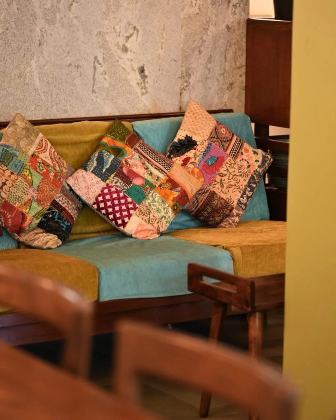 A corner sofa at TRYST layered with kantha-stitched patchwork cushions