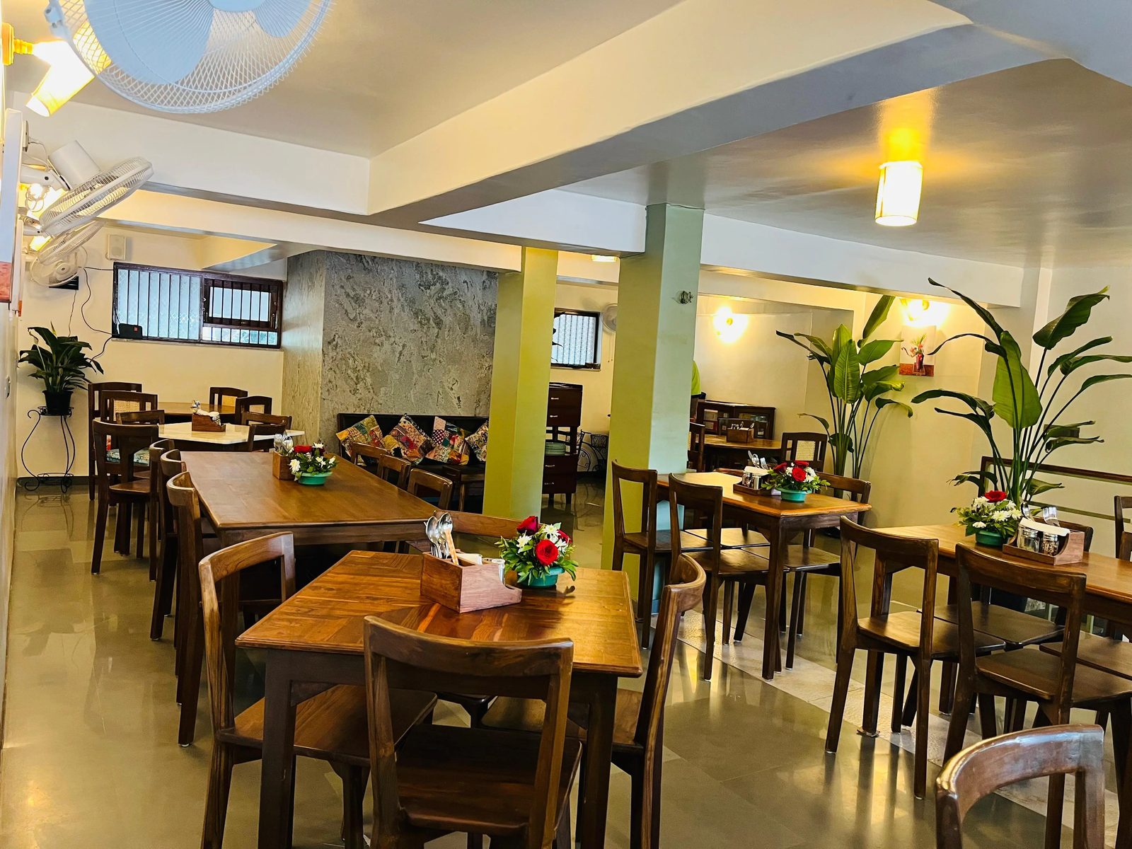 The main dining room with long wooden tables and potted plants