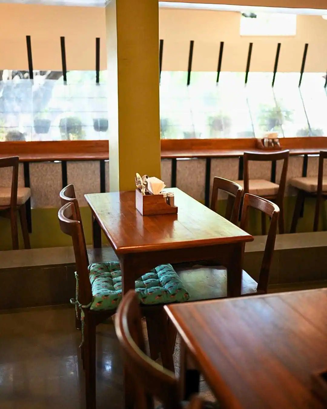 A set table by the window with cushioned bench seating