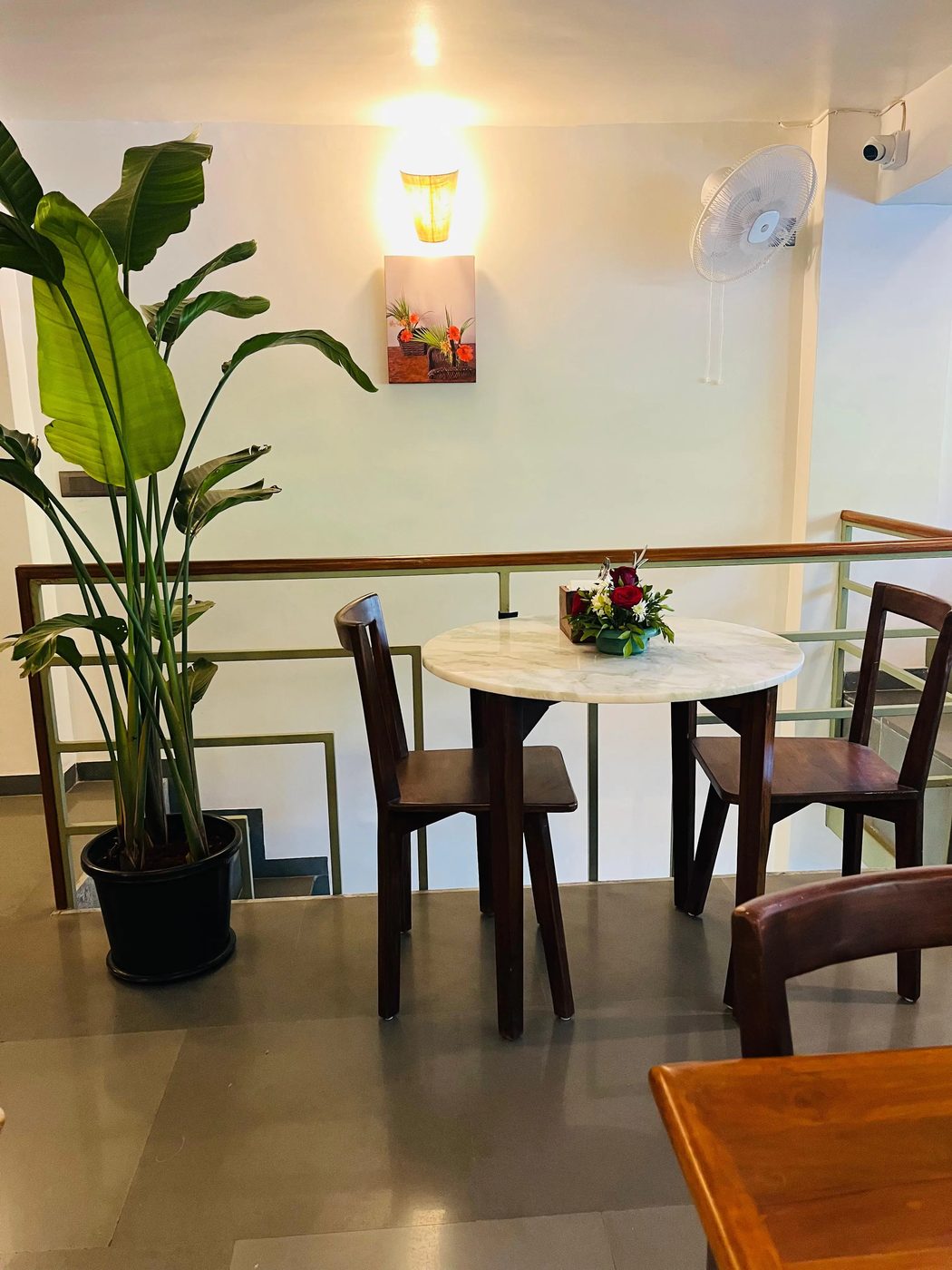 A table for two upstairs beside a tall potted plant